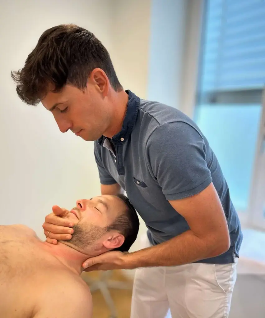 Physiotherapeut führt eine manuelle Therapie an der Halswirbelsäule eines liegenden Patienten durch