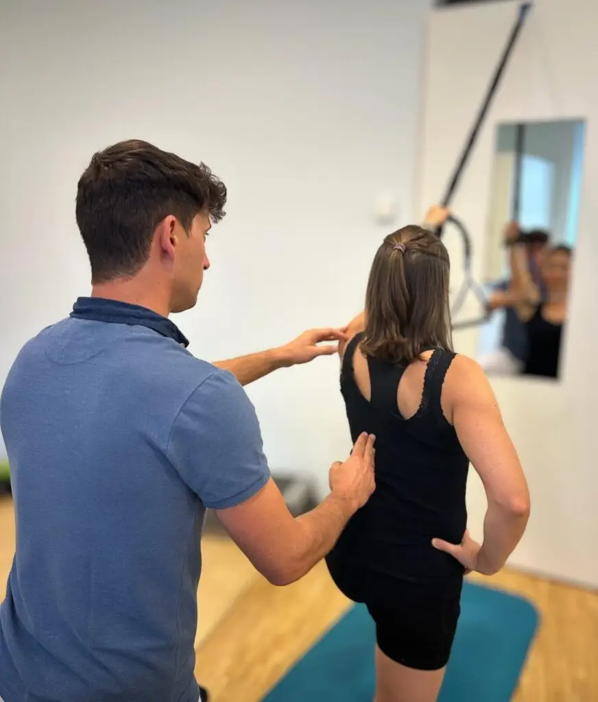 Physiotherapeut überprüft die Körperhaltung einer Patientin während einer Bewegungsausführung