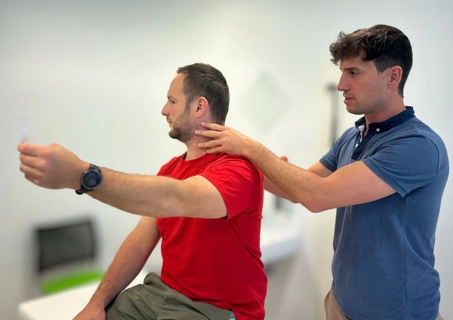 Physiotherapeut testet die Beweglichkeit von Schulter und Nacken eines Patienten